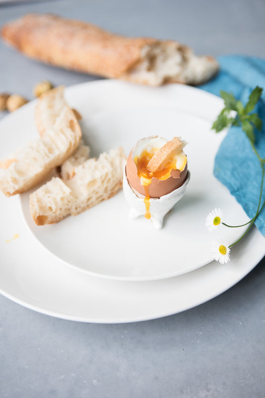 How to boil an egg, soft boiled egg with the top cut off and a piece of bread sticking out.  